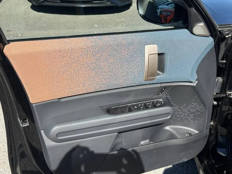 Intérieur de la porte avant gauche du MINI COUNTRYMAN 2024 Midnight Black II avec tissu bicolore et commandes électriques.