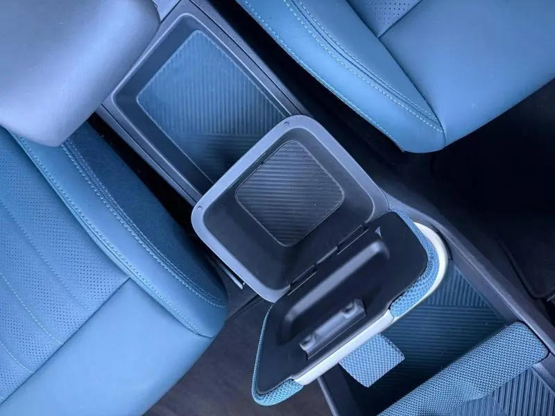 Vue plongeante sur l'intérieur bleu du MINI Countryman 2024, avec accoudoir central ouvert et rangement visible.