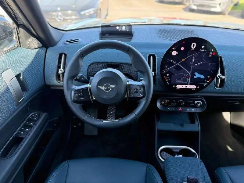 Vue intérieure avant du MINI Countryman 2024 Midnight Black II, avec tableau de bord numérique rond et volant cuir noir.