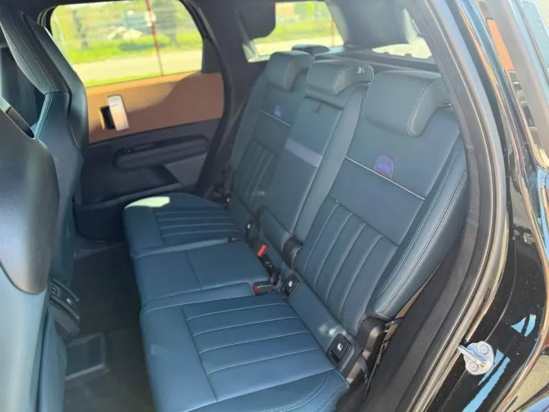 Vue intérieure côté droit des sièges arrière en cuir bleu foncé du MINI Countryman 2024 Midnight Black II avec logo MINI brodé.
