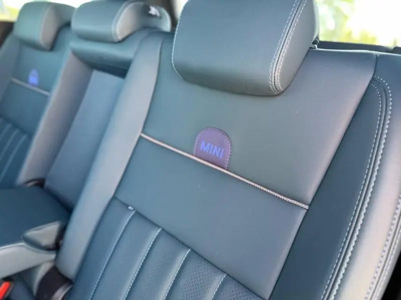 Gros plan sur la banquette arrière en cuir noir du MINI Countryman 2024 avec logo MINI brodé et surpiqûres contrastées.