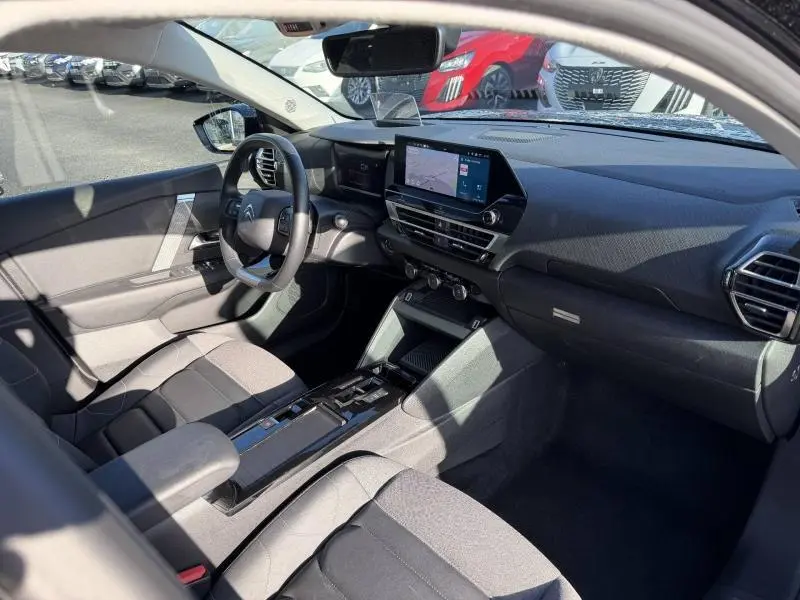 Vue intérieure côté conducteur de la Citroën C4 X 2024 noire, avec tableau de bord numérique et écran tactile central.