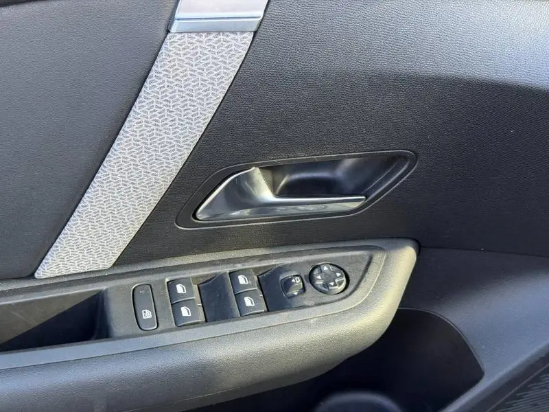 Détail de la porte côté gauche de la Citroën C4 X 2024 noire, avec commandes de vitres et insert décoratif gris.