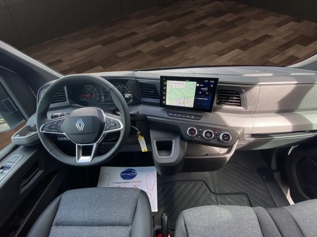 Vue intérieure avant du tableau de bord gris et volant Renault avec écran tactile central et commandes climatisation.