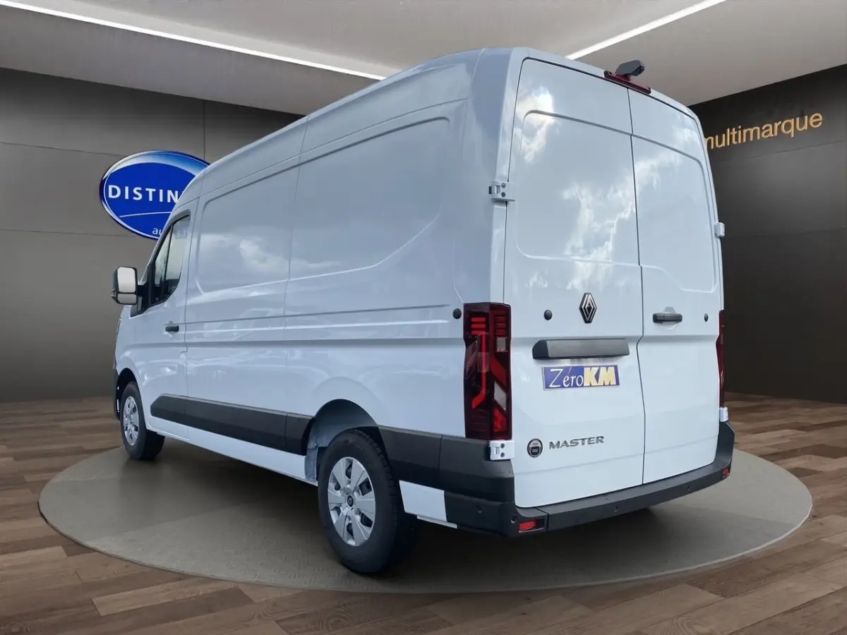 Vue 3/4 arrière droite d’un Renault Master blanc 2025 avec feux arrière LED et logo distinctif sur porte arrière.