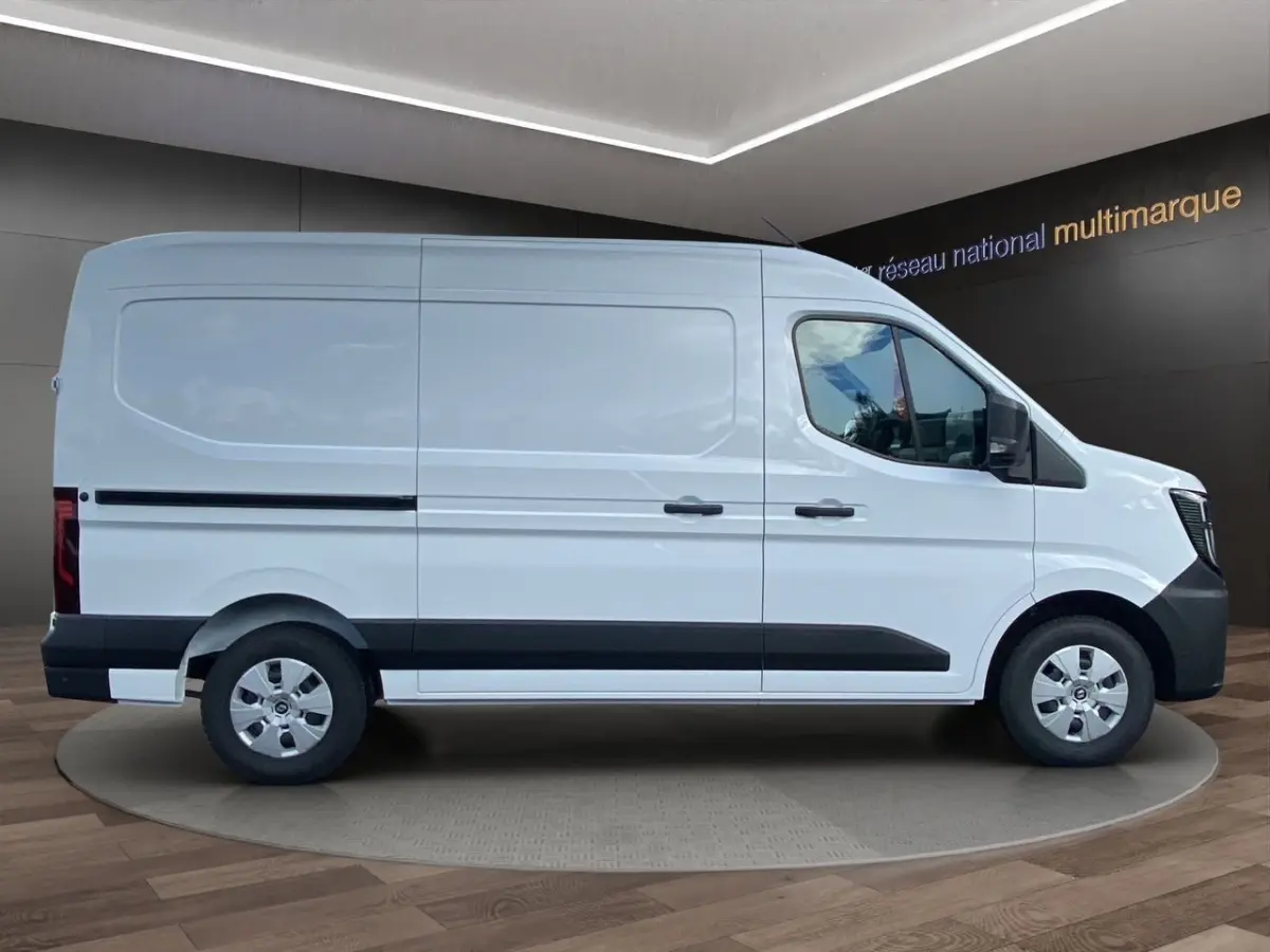 Vue de profil côté droit d’un Renault Master blanc avec bande noire basse et jantes argentées, en showroom intérieur.