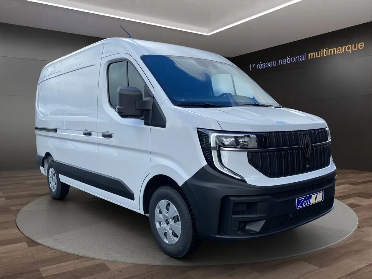 Vue 3/4 avant droite d’un Renault Master blanc avec calandre noire et phares LED distinctifs dans un showroom.