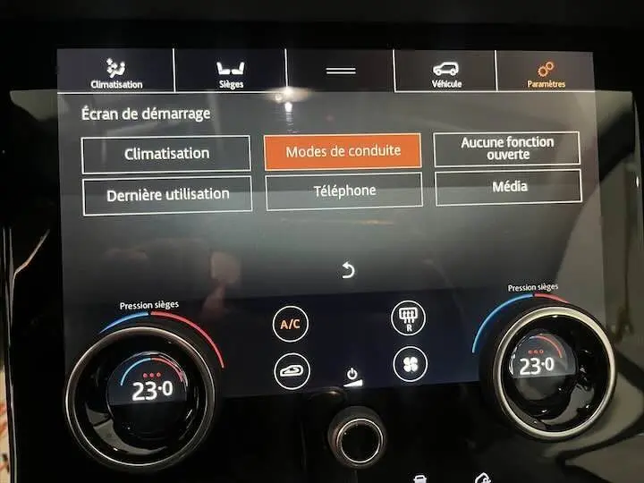 Tableau de bord tactile du Range Rover Evoque noir Santorini, affichant les réglages climatisation et modes de conduite.