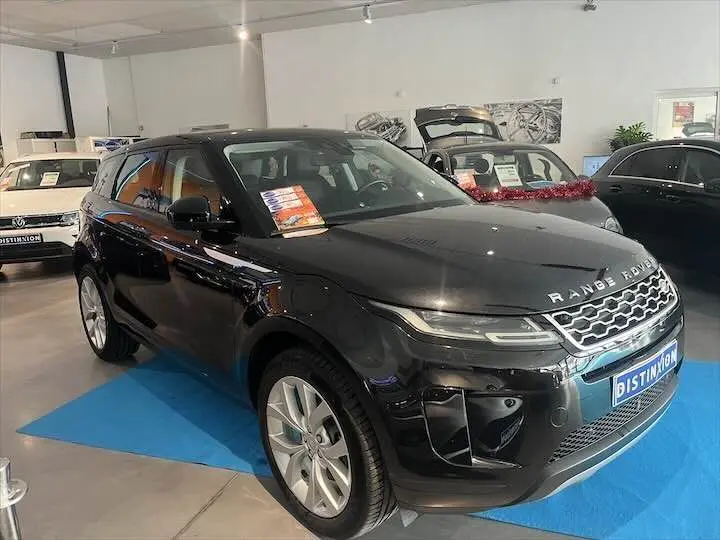 Vue 3/4 avant droite du Range Rover Evoque noir Santorini exposé en showroom avec plaques Distinxion visibles.