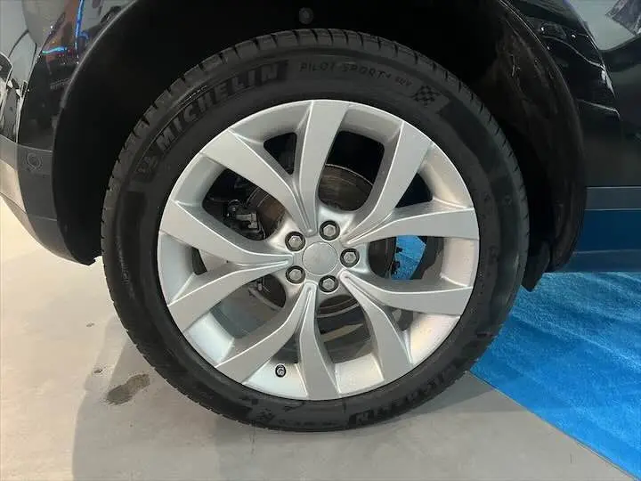 Gros plan sur la roue avant droite avec jante argentée du Range Rover Evoque noir Santorini 2020