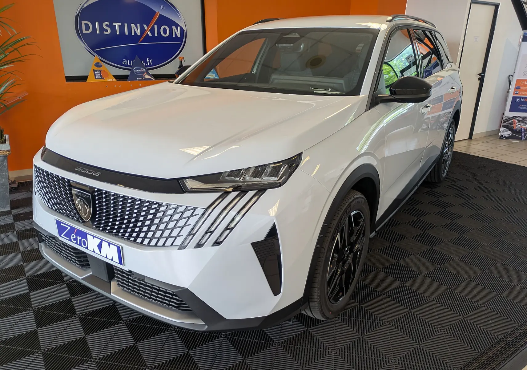 Peugeot 5008 blanc Okenite en vue 3/4 avant droit, avec calandre distinctive et jantes alliage noires.