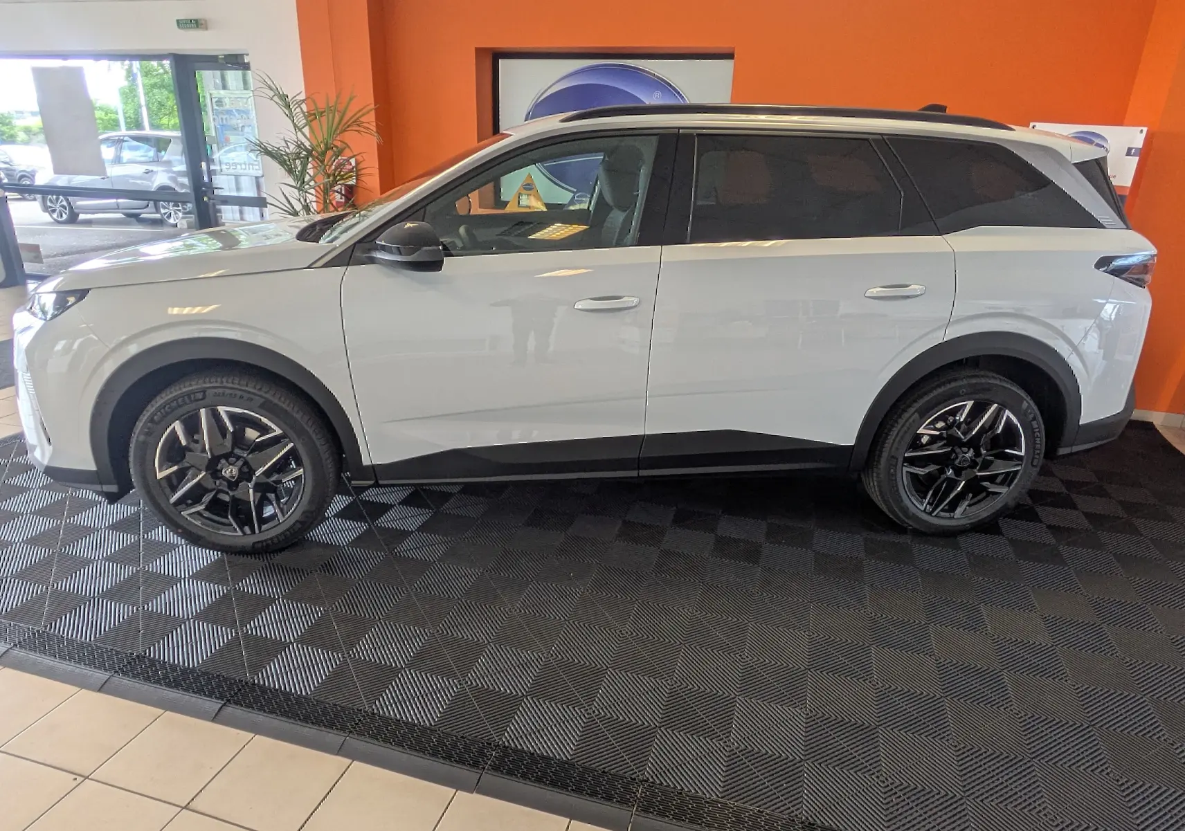 Vue de profil côté gauche du Peugeot 5008 blanc Okenite avec jantes alliage noires 19 pouces en showroom.