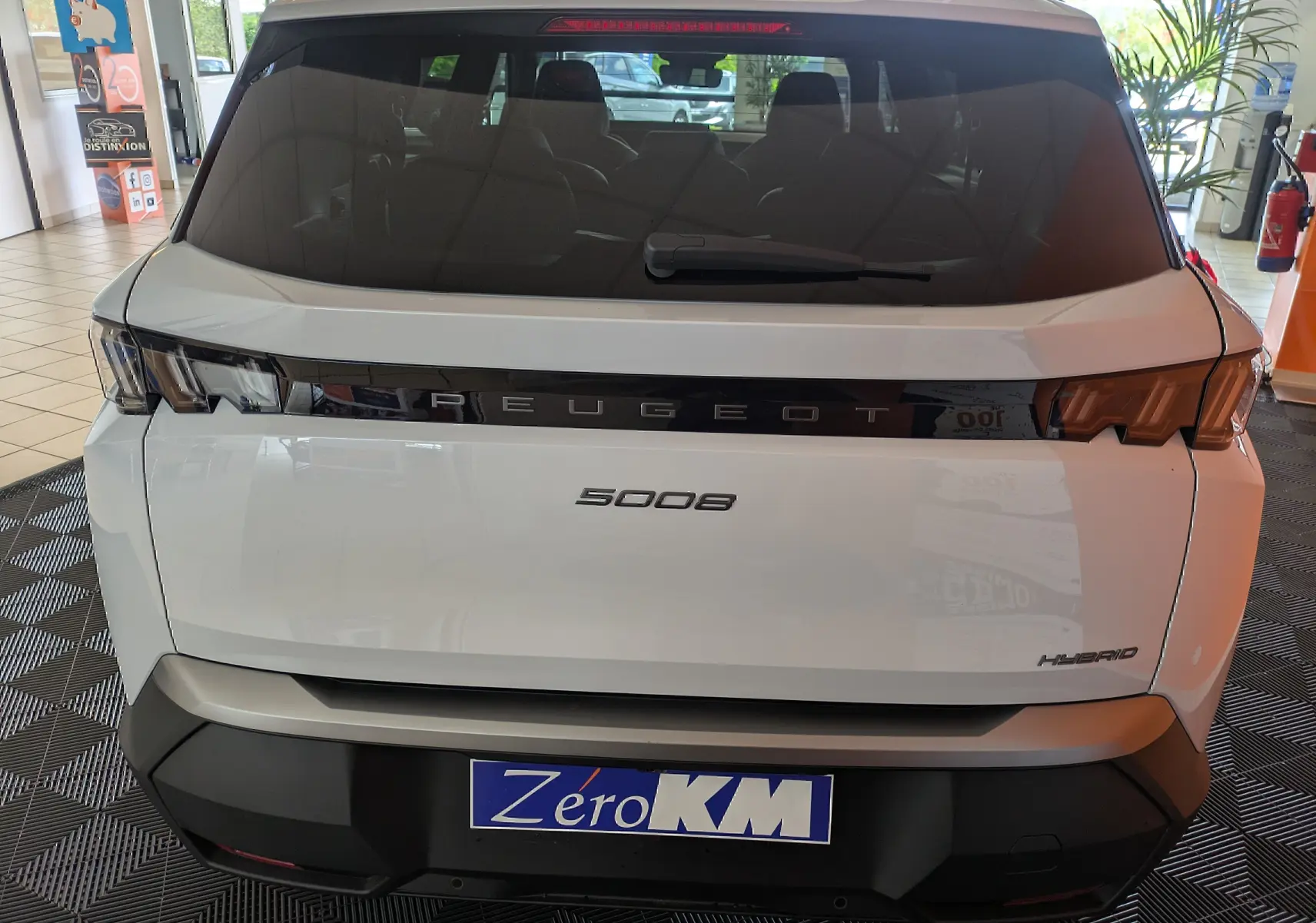 Vue arrière d’un Peugeot 5008 blanc Okenite hybride, avec logo Peugeot en bande noire et feux arrière LED distinctifs.