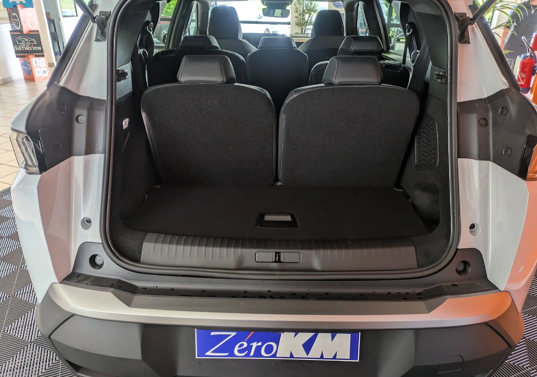 Coffre ouvert d'un Peugeot 5008 blanc Okenite, vue arrière montrant les sièges arrière et l'espace de chargement.