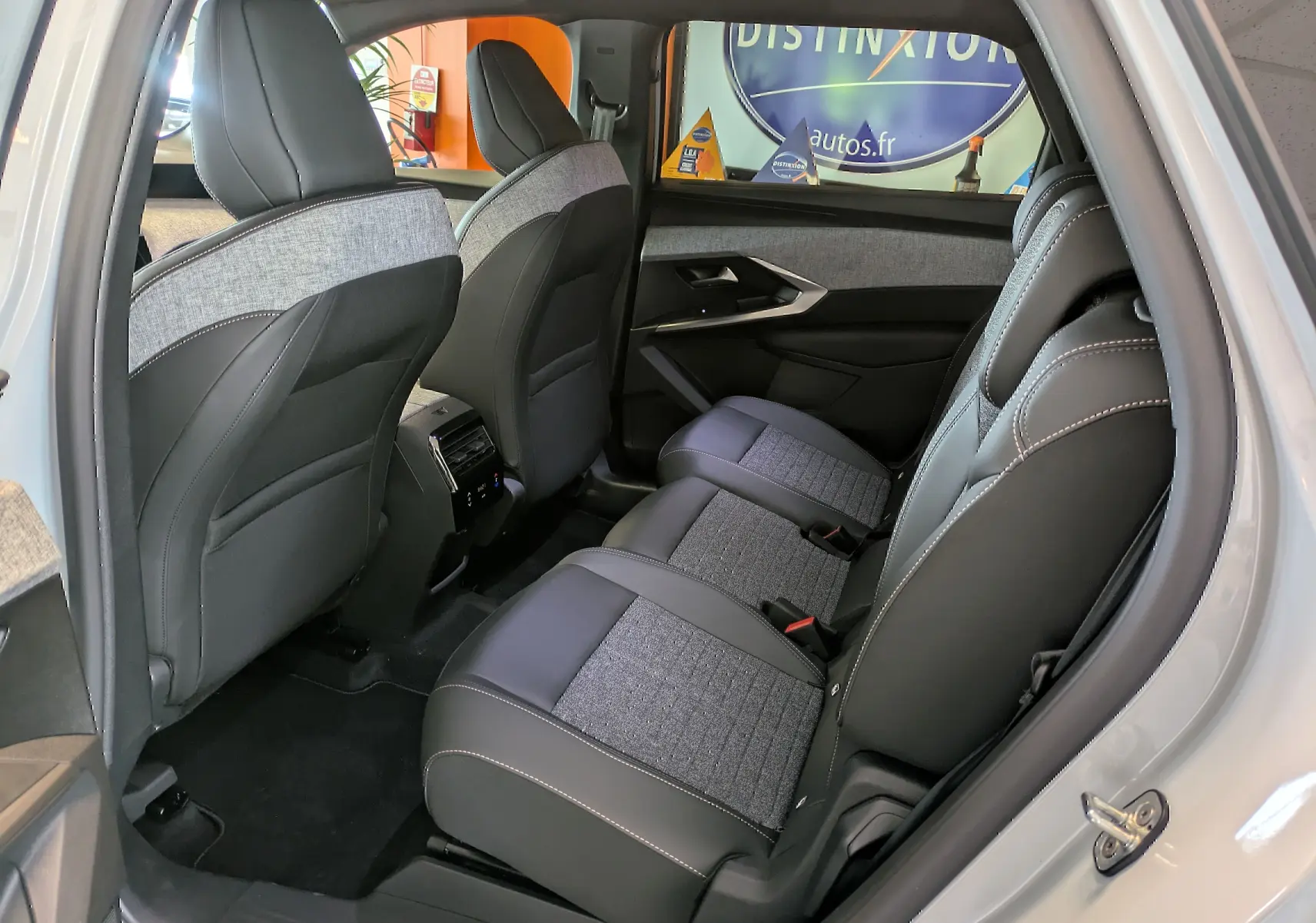 Vue intérieure côté droit arrière du Peugeot 5008 blanc Okenite, sièges tissu et cuir avec surpiqûres contrastées.