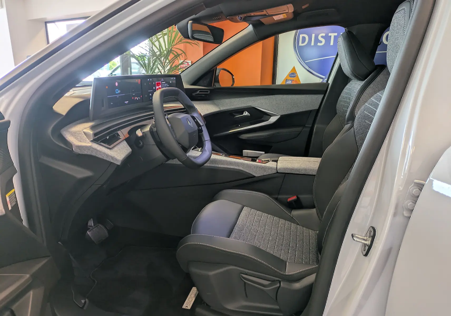 Intérieur du Peugeot 5008 blanc Okenite vu côté conducteur, avec tableau de bord numérique et sièges bi-matière gris et noir.