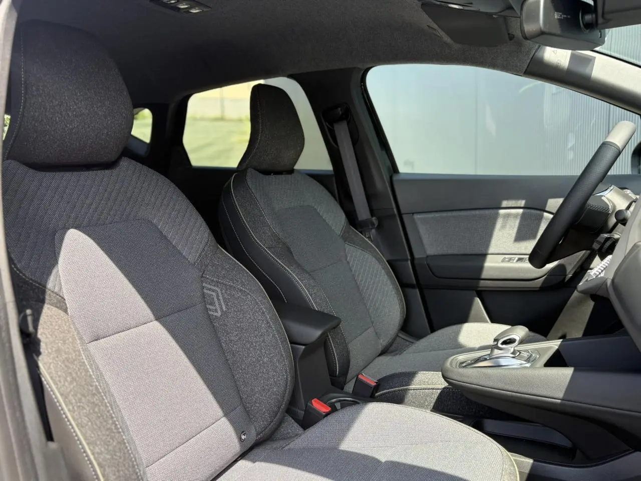 Intérieur avant du Renault Captur noir étoile 2025, sièges tissu gris et console centrale avec levier de boîte auto.