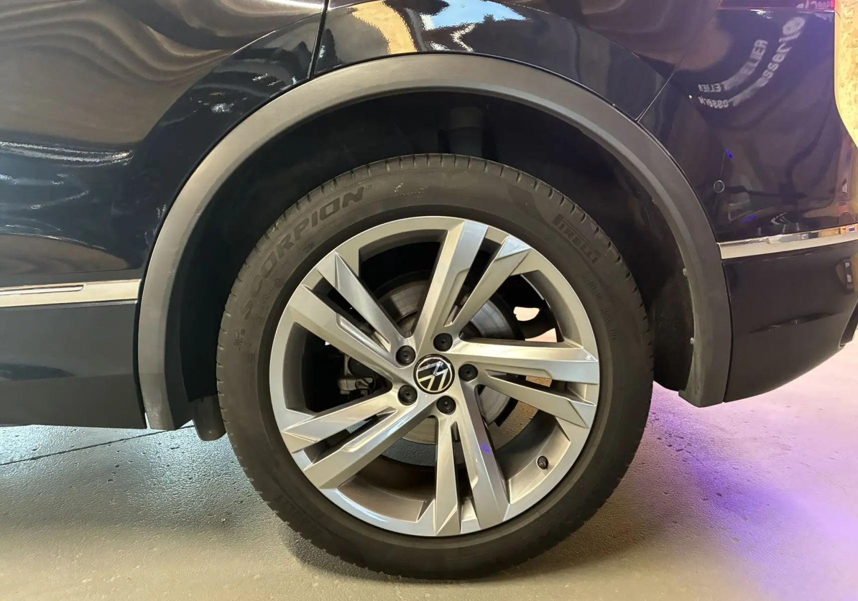 Gros plan sur la roue arrière droite noire d'un Volkswagen Tiguan 2.0 TDI 150 DSG7 R-Line avec jante alu cinq branches.