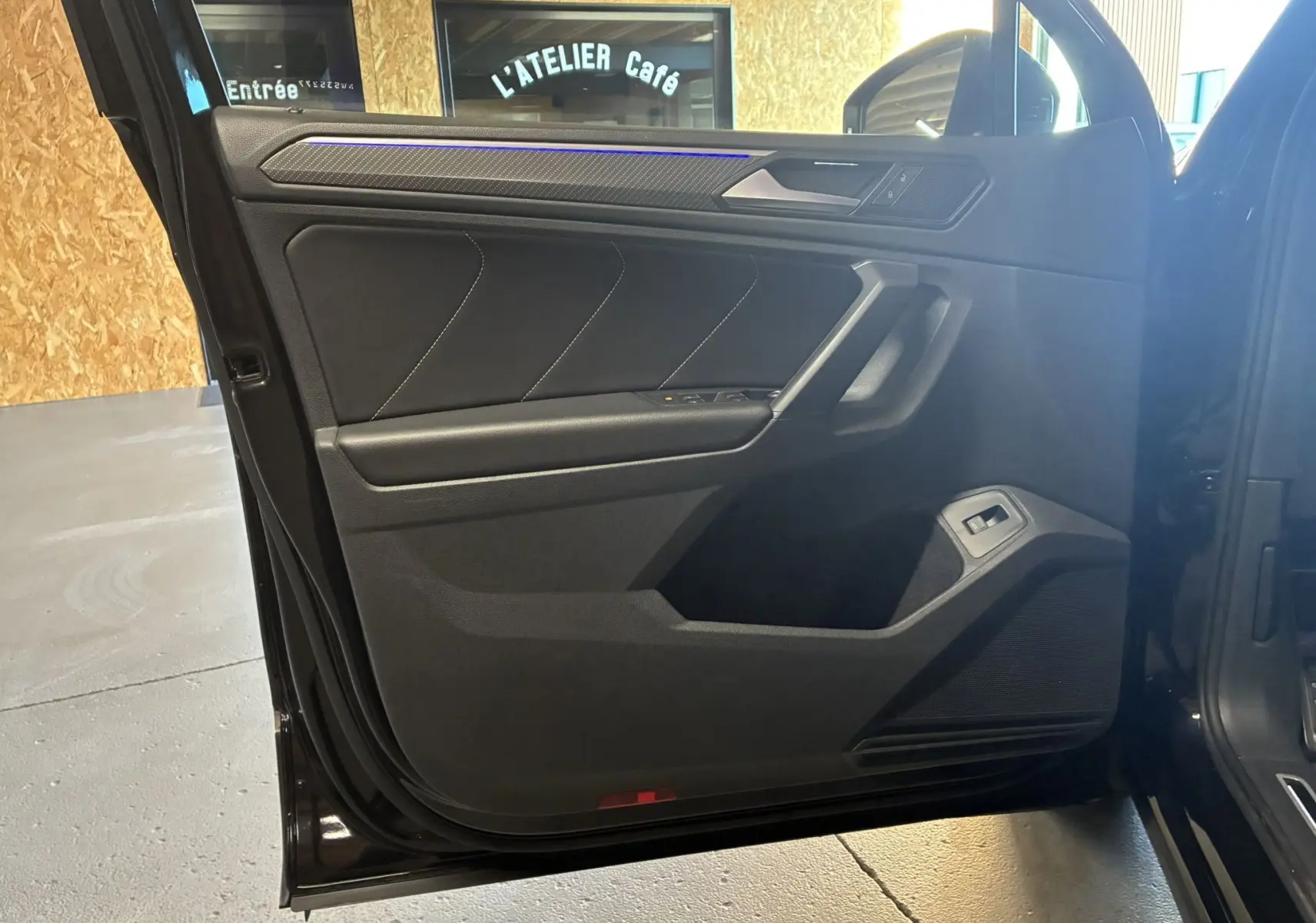 Vue intérieure de la porte avant gauche noire du Volkswagen Tiguan 2.0 TDI avec garniture tissu et commandes électriques.