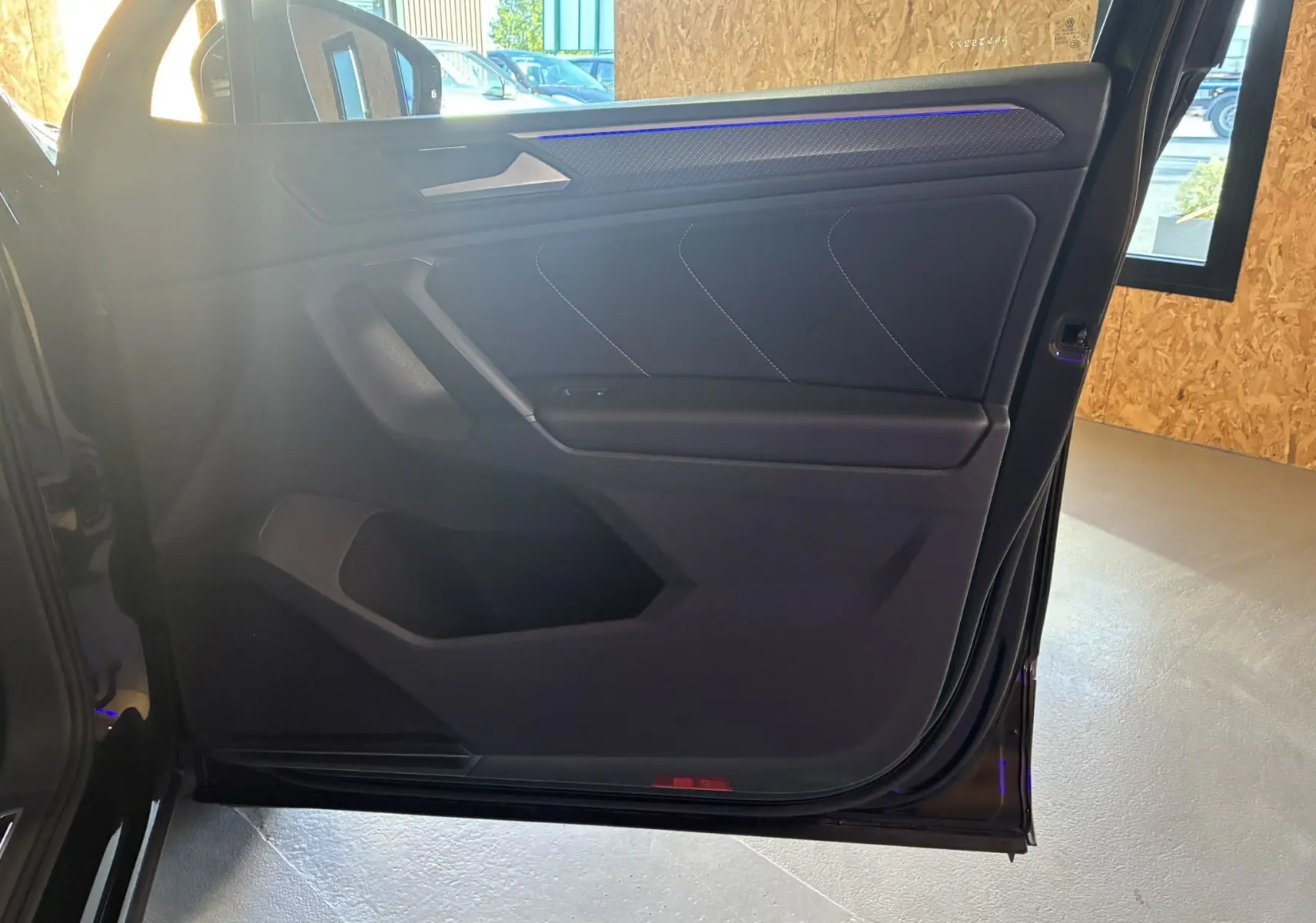 Porte arrière gauche noire du Volkswagen Tiguan 2022 avec éclairage d'ambiance bleu et garniture tissu noire.