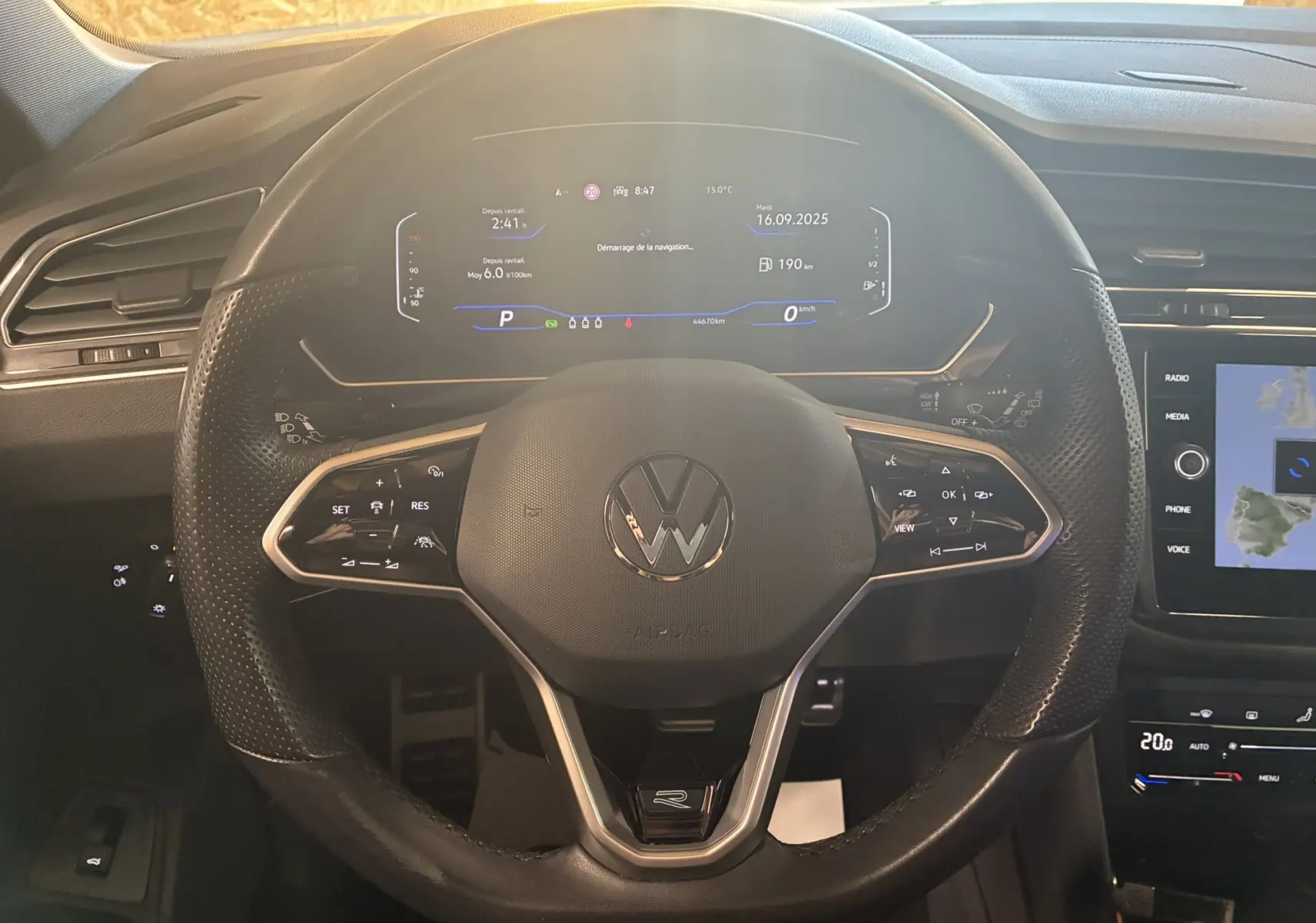 Vue rapprochée du volant cuir multifonctions noir du Volkswagen Tiguan 2.0 TDI R-Line avec tableau de bord digital allumé.