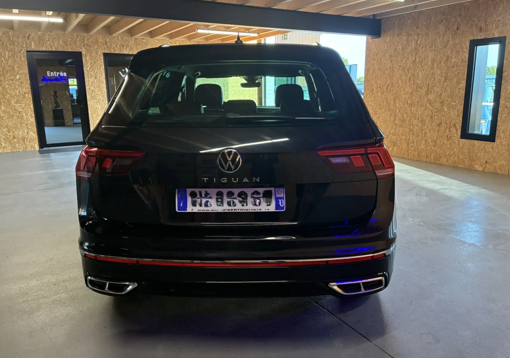 Vue arrière d'un Volkswagen Tiguan noir 2022 avec feux LED et double sortie d'échappement chromée en intérieur.