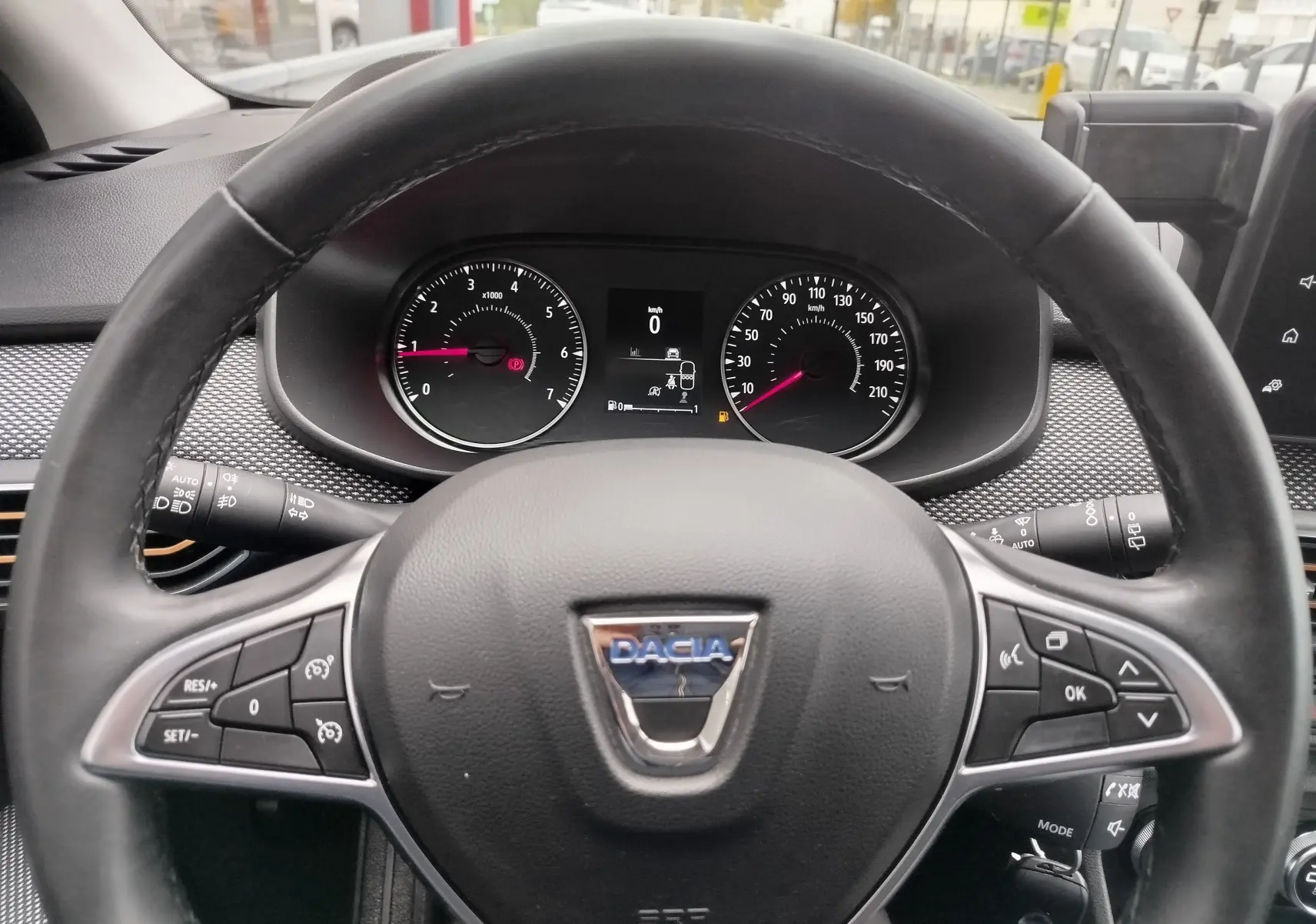 Vue rapprochée du volant noir de la Dacia Sandero Stepway 2021 avec commandes intégrées et tableau de bord digital.