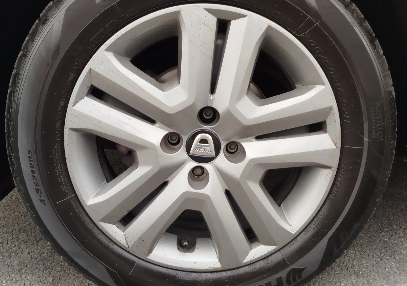 Gros plan sur la jante argentée et le pneu 4 saisons d'une Dacia Sandero Stepway blanc glacier.