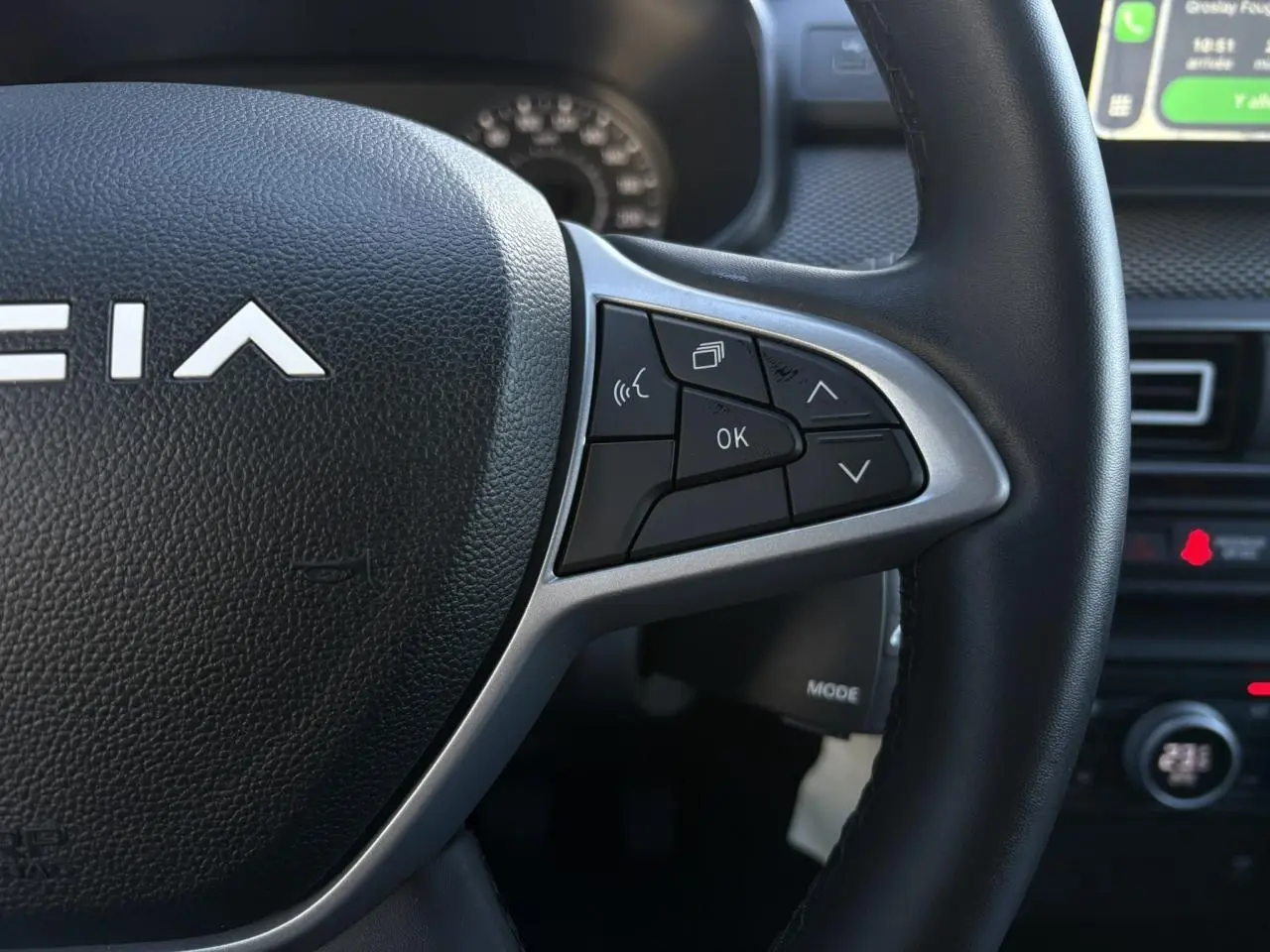 Gros plan sur le volant noir du Dacia Jogger 2025 avec commandes multifonctions et partie centrale texturée.