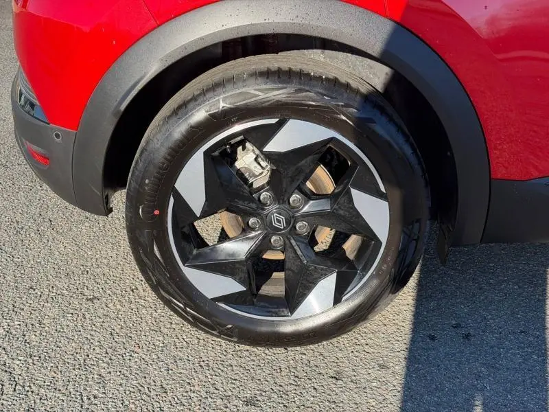 Gros plan sur la roue avant droite d’un Renault Captur Rouge Flamme avec jante noire et argentée au design étoilé.