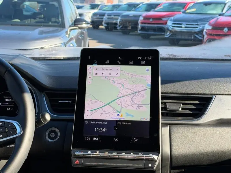 Vue intérieure du tableau de bord du Renault Captur 2025 avec écran tactile central affichant la navigation, volant partiel à gauche visible.