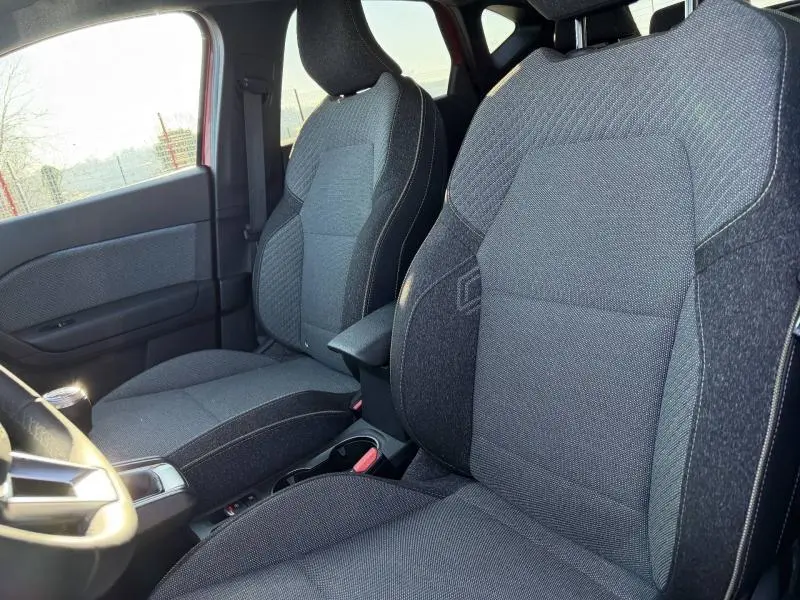 Vue intérieure côté conducteur du Renault Captur 2025, sièges en tissu gris foncé avec surpiqûres contrastantes.