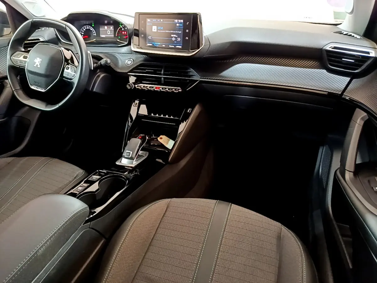 Vue intérieure côté conducteur de la Peugeot 2008 gris foncé, volant cuir multifonctions et écran tactile central.