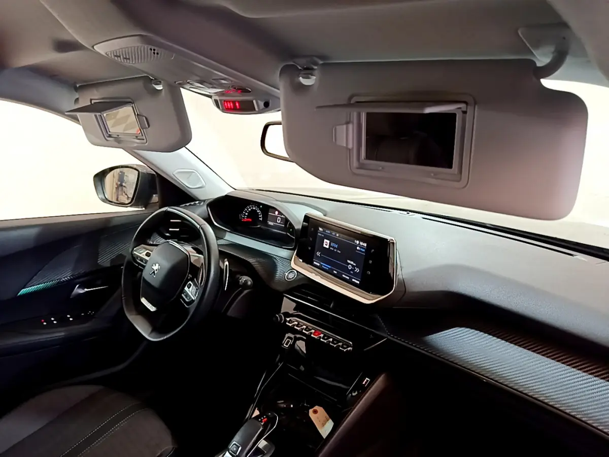 Vue intérieure avant gauche du Peugeot 2008 gris foncé, volant cuir multifonctions et écran tactile central visible.