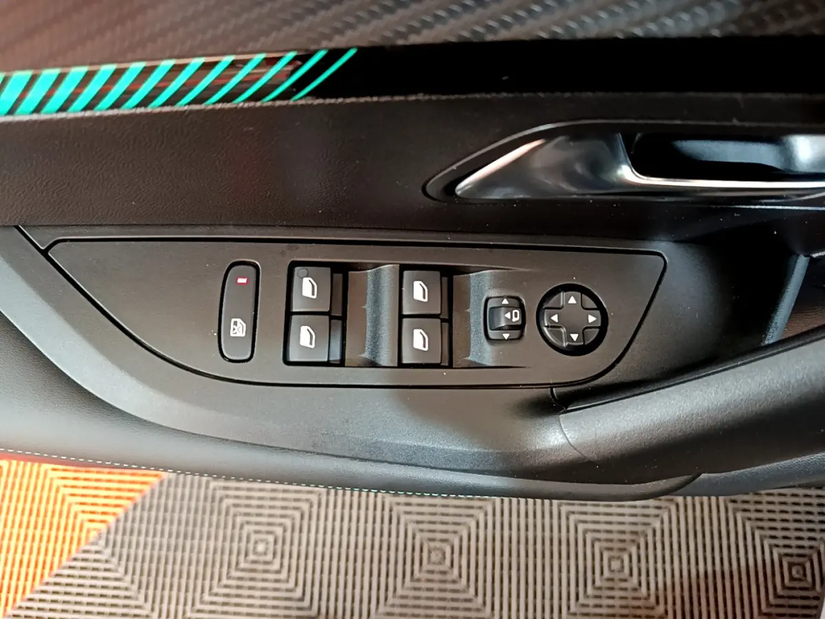 Vue rapprochée du panneau de commande des vitres côté conducteur d’un Peugeot 2008 gris foncé, avec commandes électriques.