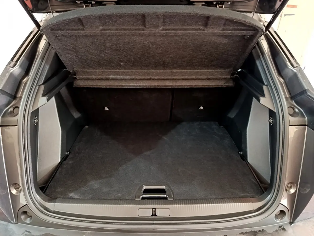Coffre ouvert vu de l'arrière d'un Peugeot 2008 gris foncé, montrant l'espace de chargement vide et la tablette relevée.