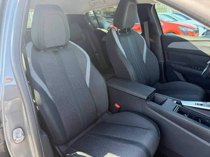 Vue intérieure des sièges avant en tissu gris et noir du Peugeot 308 1.2 Hybrid 145ch Allure 2025, côté conducteur ouvert.