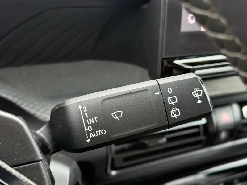 Gros plan sur la manette de commande des essuie-glaces à gauche du volant dans l’habitacle noir du Citroën C3 électrique 2025.