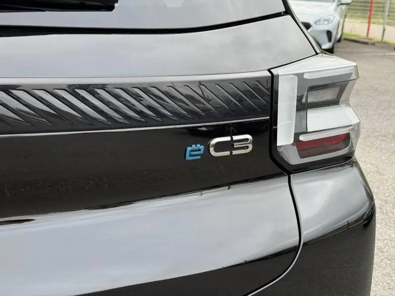 Gros plan arrière droit sur la finition Noir Perla Nera du Citroën C3 électrique 2025 avec logo ë-C3 bleu distinctif.