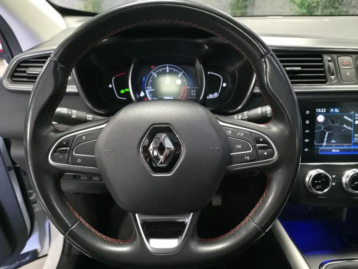 Vue rapprochée du volant cuir noir avec surpiqûres rouges et tableau de bord numérique du Renault Kadjar 2020.