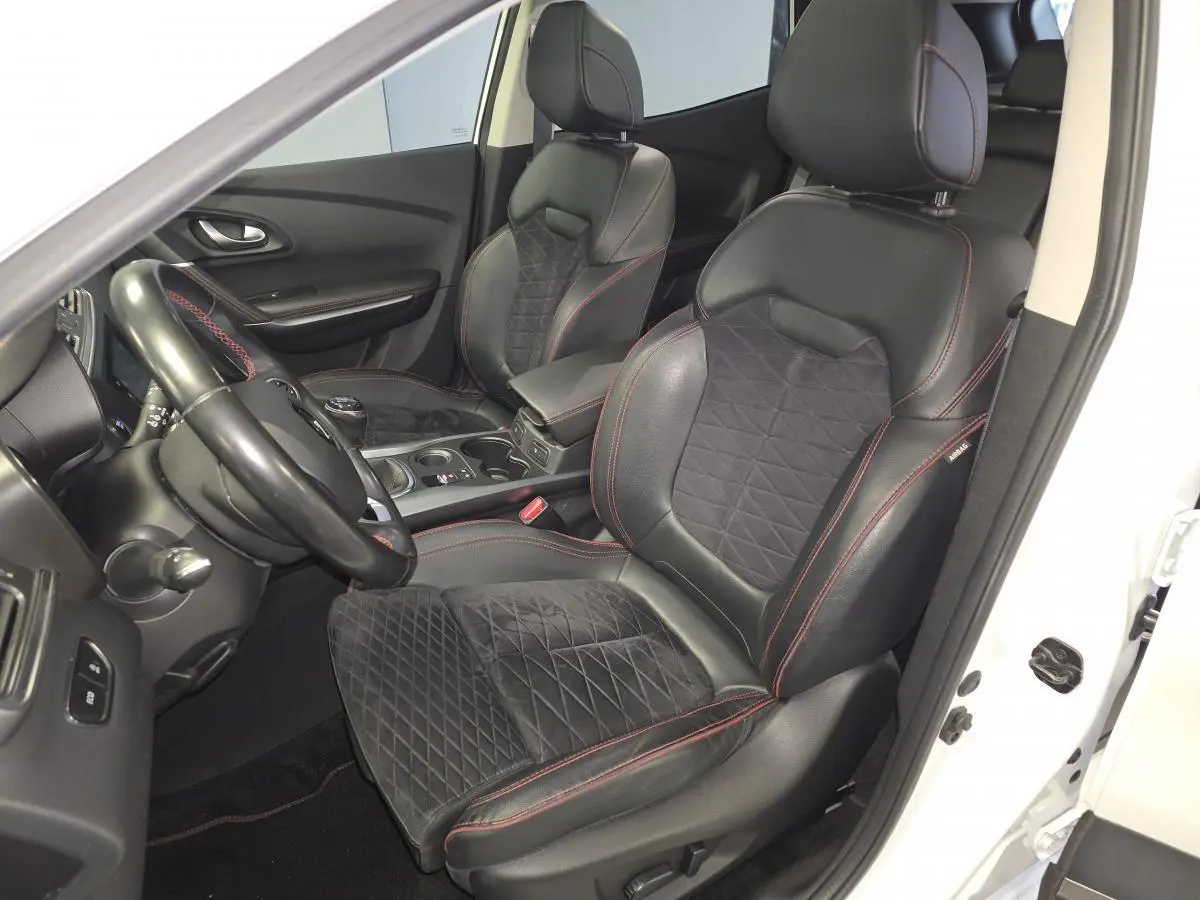Vue intérieure côté conducteur du Renault Kadjar blanc, sièges mixte cuir/Alcantara noirs avec surpiqûres rouges et volant cuir.