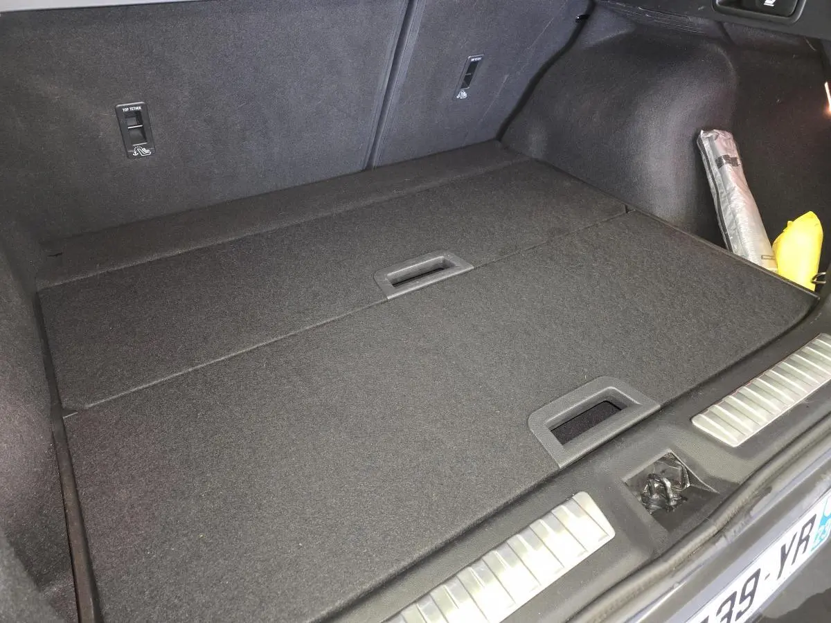 Vue du coffre fermé du Renault Kadjar blanc 2020 Black Edition, avec tapis de sol noir et accessoires rangés sur le côté droit.