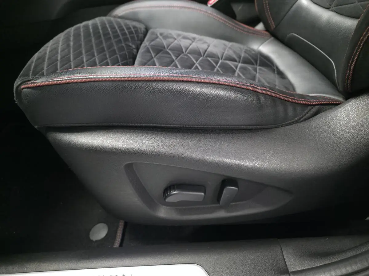Gros plan sur le côté gauche du siège avant en cuir noir avec surpiqûres rouges du Renault Kadjar 1.5 Blue dCi Black Edition.