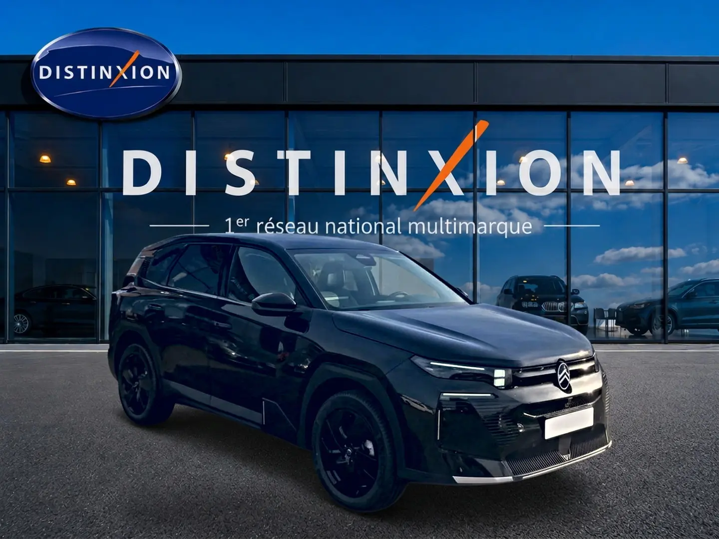 Citroën C5 Aircross noir vue 3/4 avant droit, jantes noires, devant vitrine Distinxion reflet ciel bleu.
