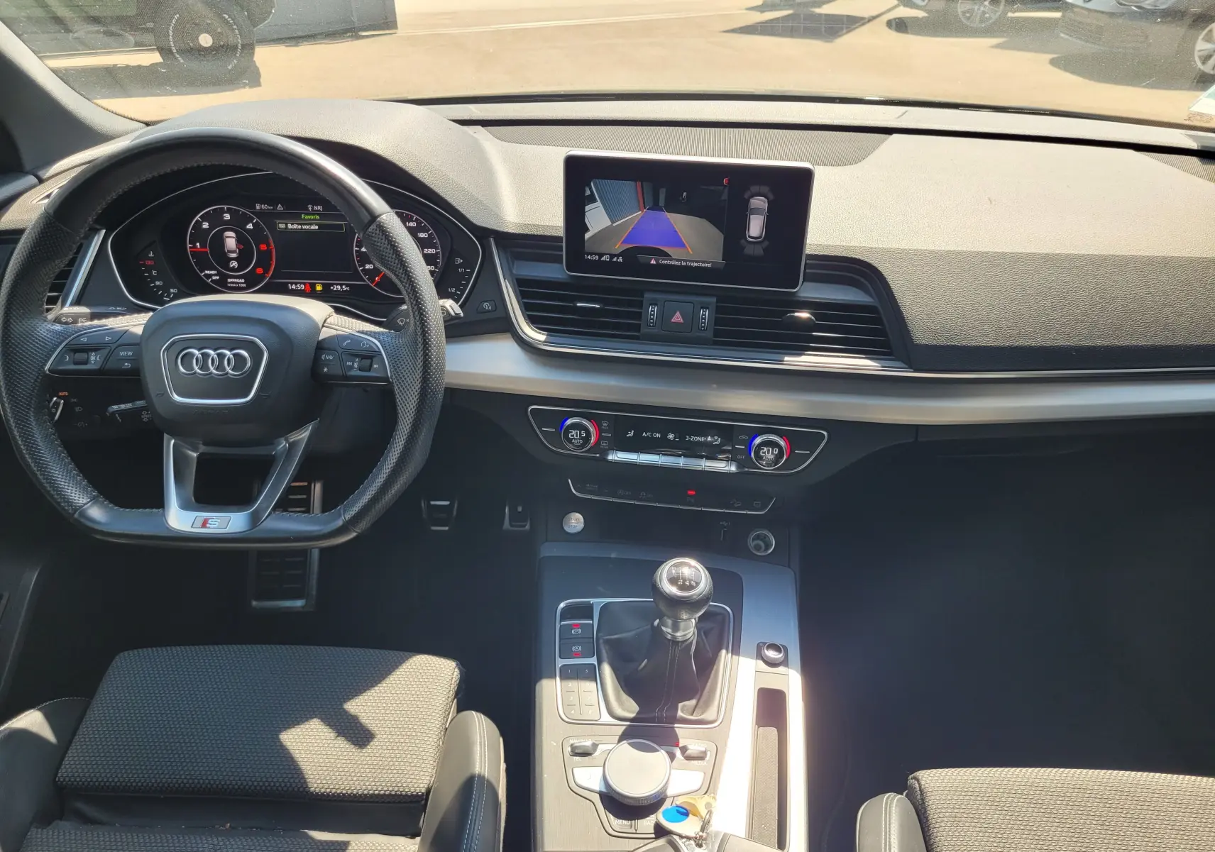 Vue intérieure avant de l'Audi Q5 noire 2018, mettant en valeur le volant S Line, écran central et levier de vitesse manuel.