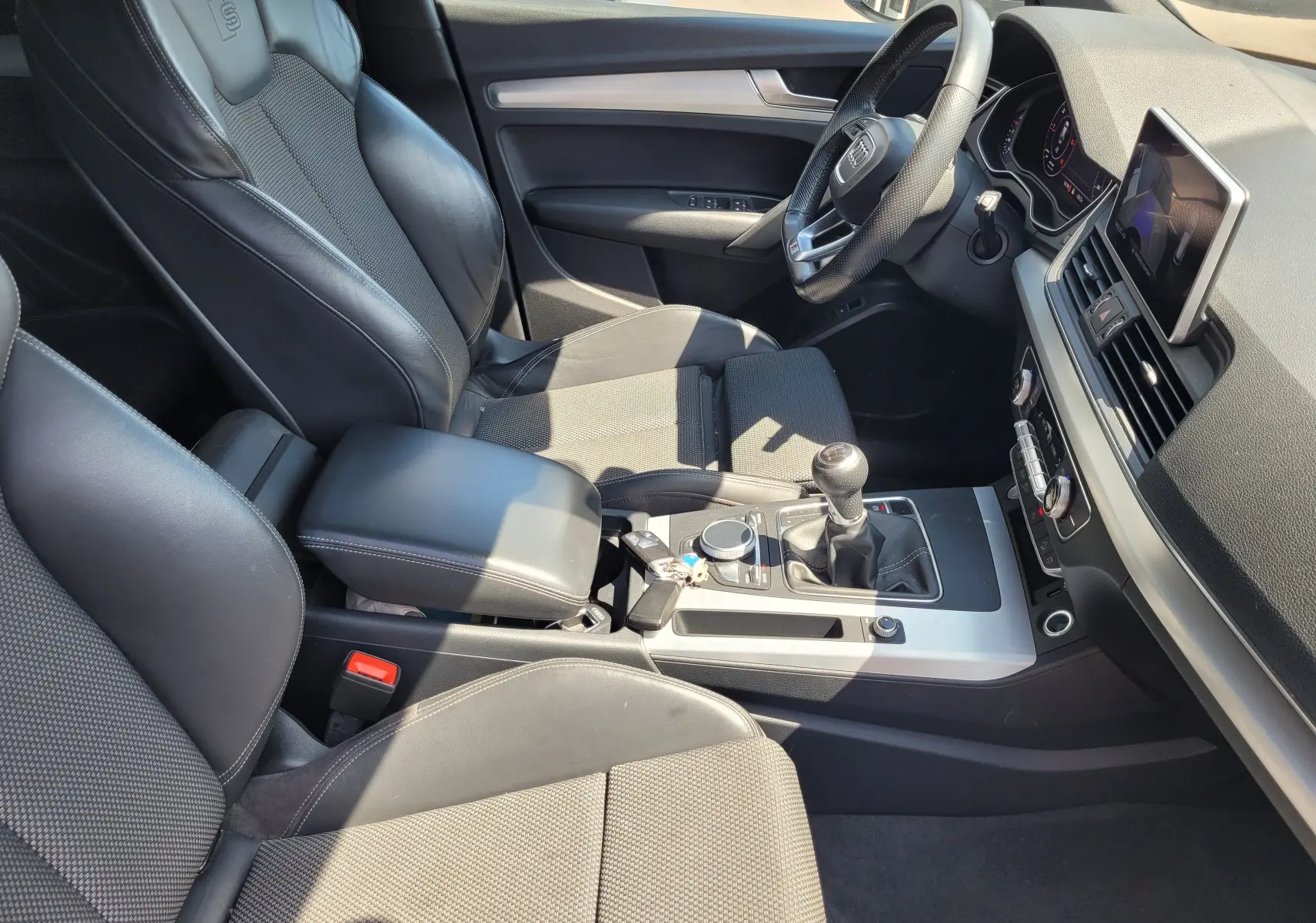 Intérieur noir de l'Audi Q5 2018 S Line, vue côté conducteur montrant sièges sport, volant et console centrale manuelle.