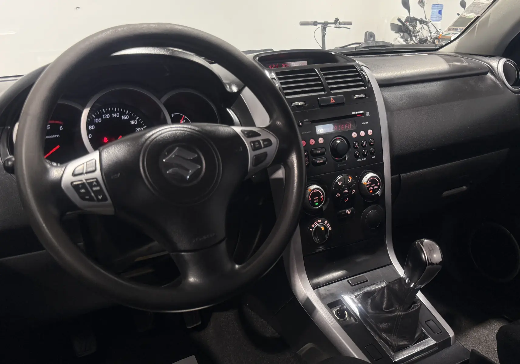 Intérieur du Suzuki Grand Vitara 2007, vue du poste de conduite avec volant, tableau de bord et levier de vitesses manuel.