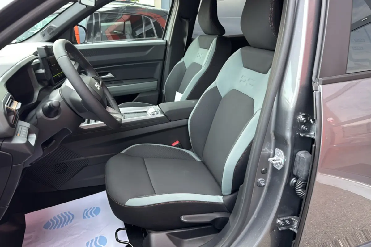 Intérieur avant droit du Dacia Bigster Hybrid 155 Extreme Plus 2025 en gris schiste, sièges bicolores avec logo embossé.