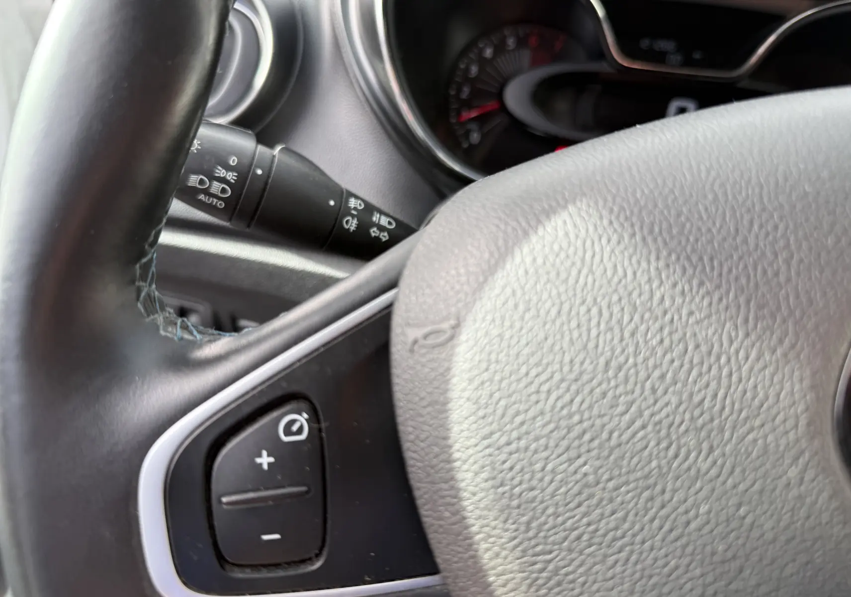 Gros plan sur le volant noir du Renault Captur 2017 avec commandes intégrées et tableau de bord en arrière-plan flou.