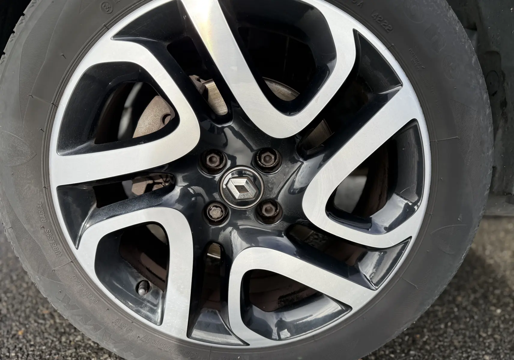 Gros plan sur la jante alliage bicolore noire et argent avec logo Renault au centre du Renault Captur blanc 2017.